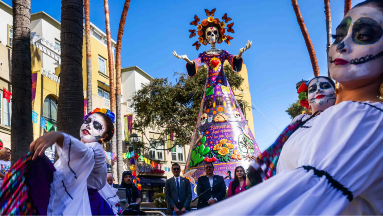 girls dancing in front of La Catrina scultupre