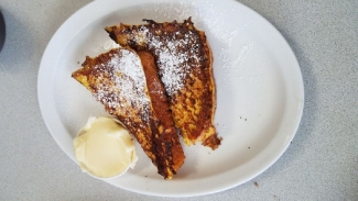 Two pieces of french toast, sprinkled with powdered sugar.