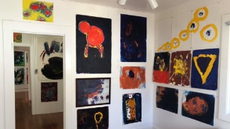 Interior corner of Art Cottage, featuring modern paintings packed closely together